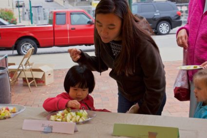 A woman and her child at the Bloomington Farmers' Market sampling produce